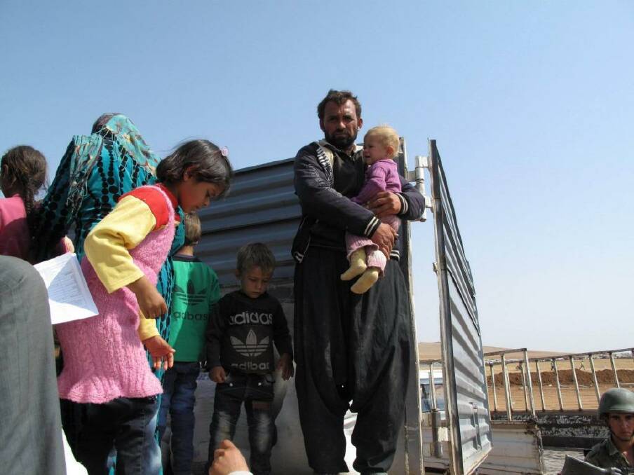 Ali Bourzan Isa holds his youngest daughter in the back of a truck that took them from the Turkish-Syrian border.  Photo: Ruth Pollard