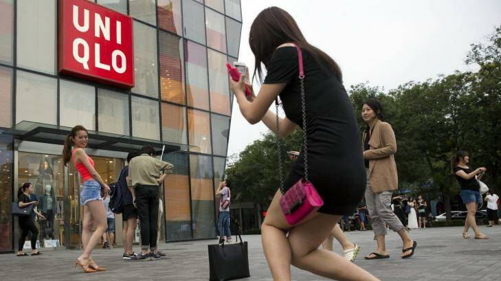 A Chinese woman poses for photo outside the Uniqlo store in Beijing where a steamy video was filmed. Photo: Ng Han Guan