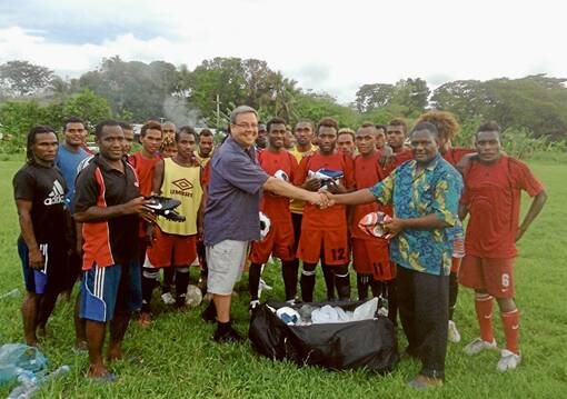 Craig Lawrence is pictured presenting soccer boots and equipment to the Solomon Islands national soccer team recently.