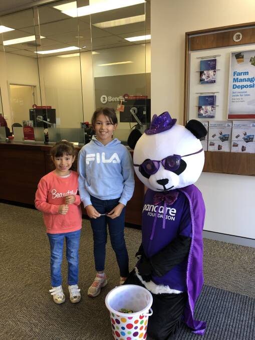 It's easy being purple!: Panky the Panda makes friends with the Raptis sisters during his Harden to Murrumburrah walk, calling through the Bendigo Bank on the way. Picture: Jody Potts