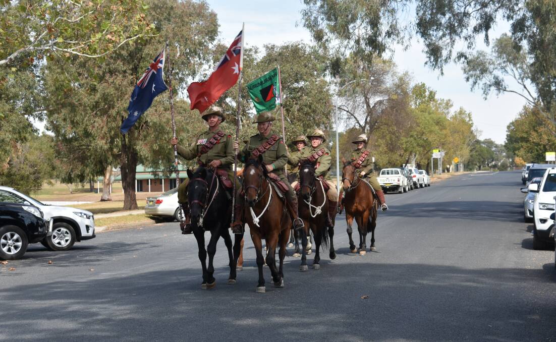 Members of the Harden Murrumburrah Light Horse Troop ride toward the Cenotaph in Newson Park.