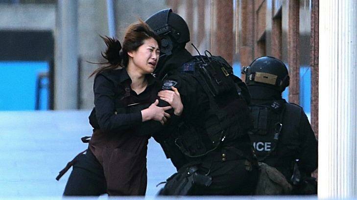 One of the women held hostage inside the cafe for several hours runs into the arms of police after being freed.  Photo: AP Photo/Rob Griffith