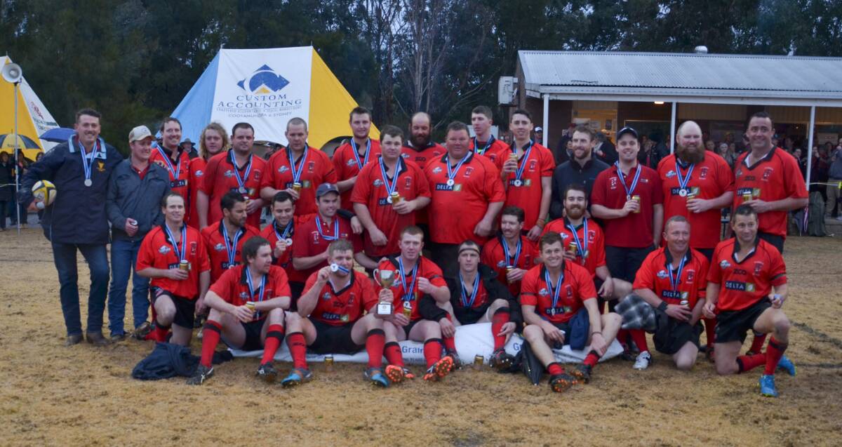 CHAMPIONS: The Harden Red Devils pose with medals and the GrainCorp South trophy at Roberts Park on Saturday. Photo: Declan Rurenga